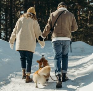 Older Couple Walking in Snow with Dog